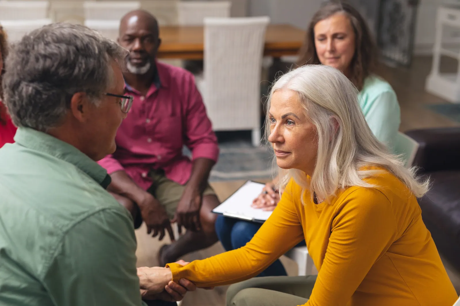 Grupo de adultos mayores sonriendo y conversando en una sesión de apoyo en Escazú