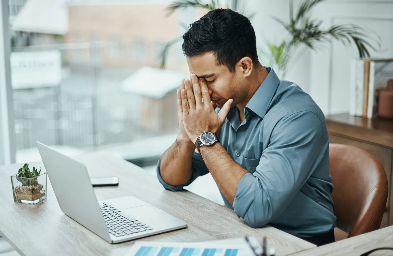 Hombre agotado frente a su computadora, en busca de terapia para el estrés laboral en Escazú