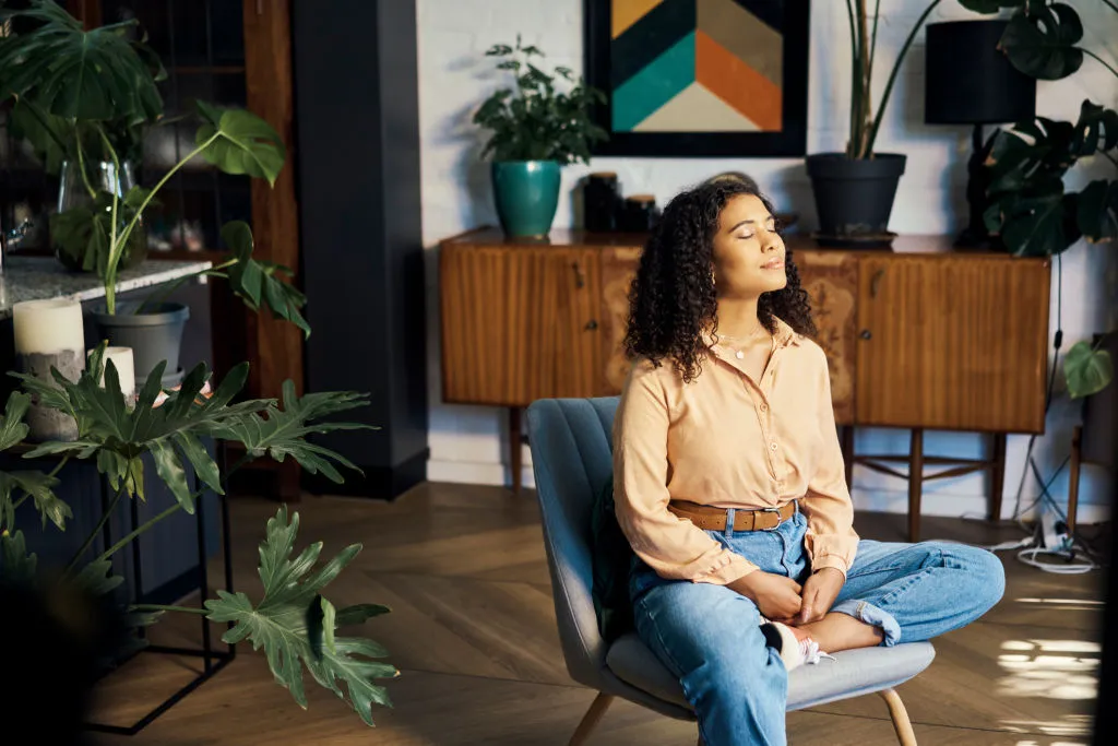 Mujer sentada con los ojos cerrados practicando mindfulness