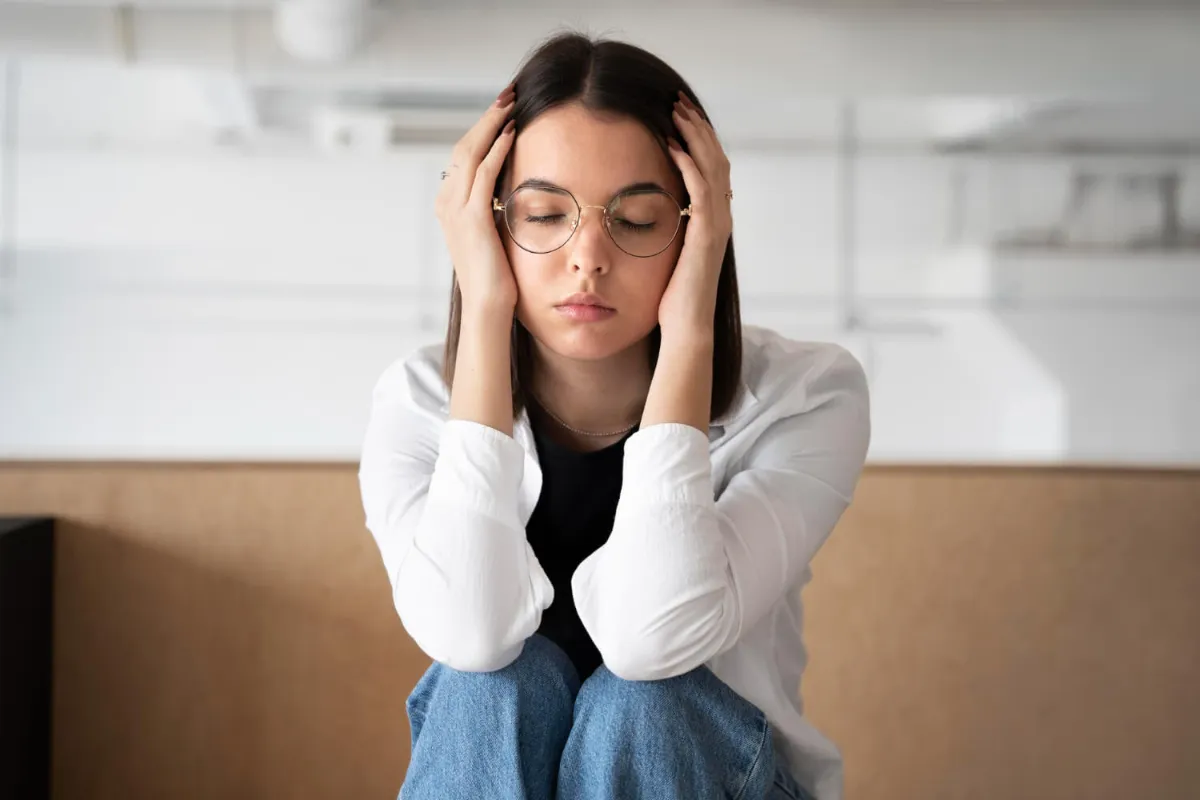 Mujer joven con las manos en la cabeza, angustiada por la ansiedad